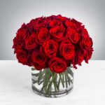 A bouquet of vibrant red roses in a clear glass vase.