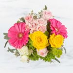 A vibrant bouquet with pink gerberas, yellow roses, and light pink roses.