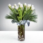 Elegant white tulips arranged with greenery in a clear glass vase.