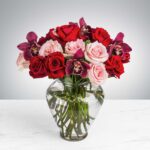 A bouquet of red and pink roses in a clear glass vase.
