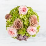 Top view of a bouquet with pink and brown roses and green hydrangeas.