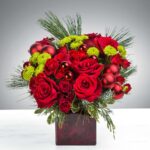 Elegant bouquet of red roses and green chrysanthemums in a square vase.