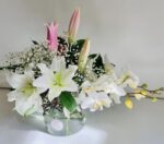 Elegant floral arrangement with white lilies and pink buds in a glass vase.