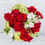 A vibrant bouquet of red roses and white flowers against a marble background.