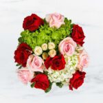A bouquet with red, pink, and white roses accented by green leaves.