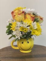 Yellow smiley face mug holding a cheerful bouquet of yellow and white flowers.