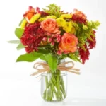 A vibrant bouquet of mixed flowers in a clear glass jar tied with twine.