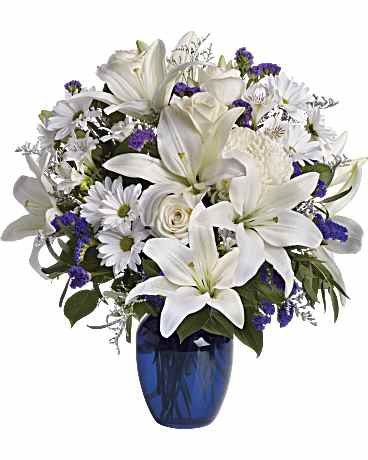 Elegant bouquet of white lilies and purple flowers in a blue vase.