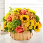 A vibrant bouquet of sunflowers, roses, and greenery in a basket.