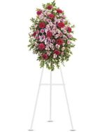 Elegant floral arrangement on a white stand with pink and red flowers.