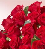 A dense bouquet of vibrant, deep red premium long-stem roses with lush green leaves.