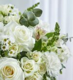 A lush and elegant bouquet of various white flowers including roses, carnations, alstroemeria, and daisies, accented with green eucalyptus leaves and snapdragon buds.