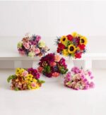 Five distinct, colorful mixed floral bouquets arranged on white pedestals and surfaces against a clean white background.