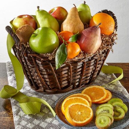 A premium woven dark brown wicker gift basket filled with a variety of fresh fruits, including green and red apples, pears, and oranges, accompanied by a plate of sliced kiwi and oranges in the foreground.