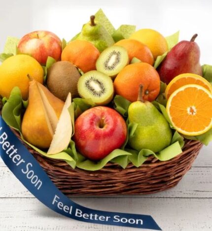 A large, woven brown wicker basket overflowing with a variety of fresh fruits including apples, pears, oranges, and kiwis, set against a white wooden background.